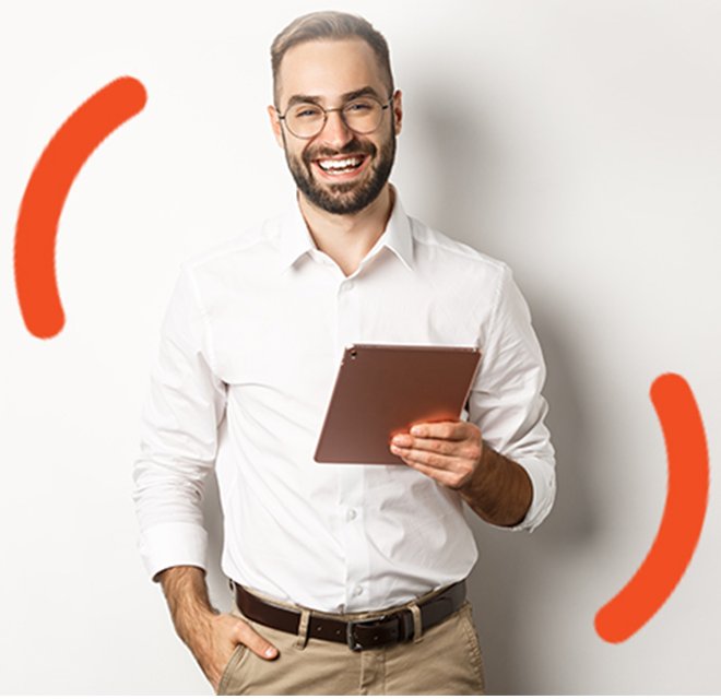 Homem olhando em sua direção, sorrindo, com a mão direita no bolso da calça e em sua mão esquerda segurando um tablet.