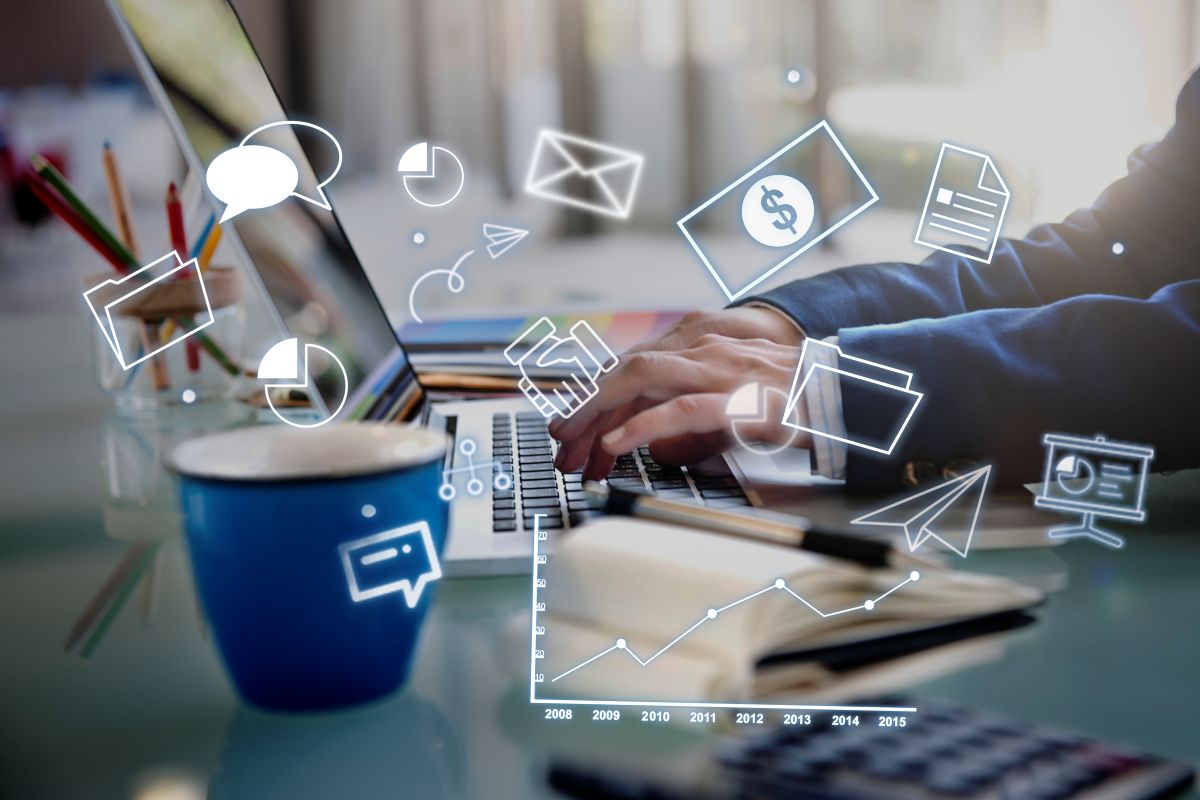 Pessoa usando notebook com ícones digitais de marketing, comunicação, vendas e análise de dados.
