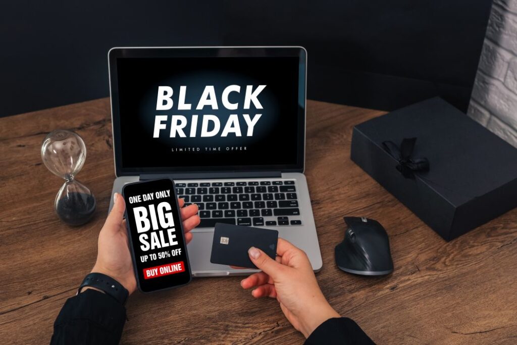 Notebook e celular exibem ofertas de Black Friday para TI com cartão de pagamento sobre a mesa.