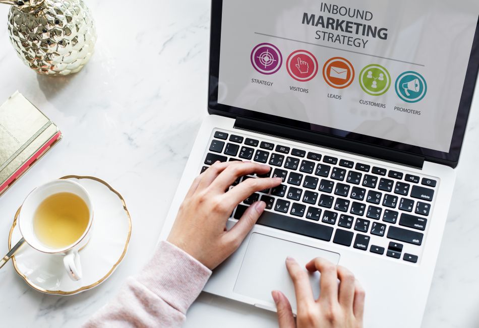 Notebook exibe estratégia de inbound marketing com etapas de visitantes, leads, clientes e promotores.